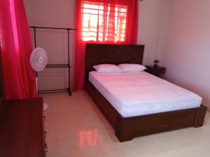 a bedroom with a bed and a window with red curtains at Complexe La Belle Rosie in Les Cayes