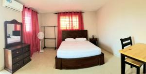 a bedroom with a bed and a table and a desk at Complexe La Belle Rosie in Les Cayes