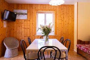 a dining room with a table with chairs and a vase of flowers at Gites des Gentianes in Morbier