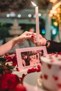 a person holding a candle on a table with a cake at Ada Palas Buyukada in Buyukada