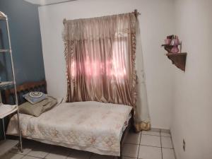 a small bedroom with a bed and a curtain at Comfortable and equipped house in Rioverde in Río Verde