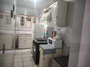 a small kitchen with white cabinets and a stove at Comfortable and equipped house in Rioverde in Río Verde
