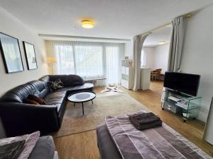 a living room with a leather couch and a television at Apartment Sunnmatt 752 by Interhome in Engelberg