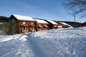 een gebouw bedekt met sneeuw naast een besneeuwde weg bij Markusfolks Gård in Torsby