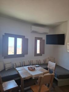 a living room with a table and chairs and a couch at ACHERONAS Residences in Serifos Chora