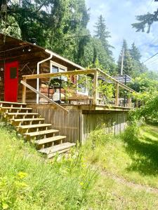 a wooden house with stairs and a red door at Cedar House Ocean View & Access in Roberts Creek