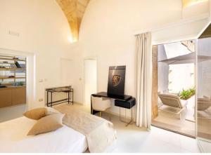 a white bedroom with a bed and a desk at Casa Novecentoundici in Castrignano deʼ Greci