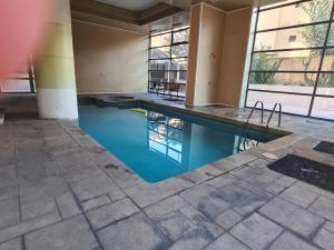 a swimming pool in a building with blue water at Manuel Montt Spot by AndesPlus in Santiago