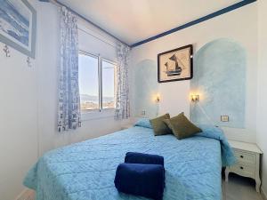 a bedroom with a blue bed and a window at Apartment Club Nautic-17 by Interhome in Empuriabrava