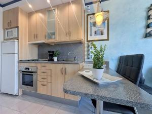 a kitchen with wooden cabinets and a table with a potted plant at Apartment Club Nautic-17 by Interhome in Empuriabrava