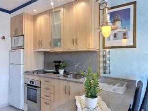 a kitchen with wooden cabinets and a sink at Apartment Club Nautic-17 by Interhome in Empuriabrava +32 photos