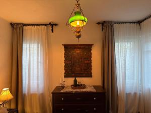 a room with a dresser and a chandelier and two windows at Casa Alexandra Slătineanu in Bran
