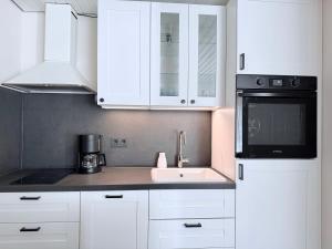 a kitchen with white cabinets and a sink and a microwave at Ferienwohnung Eulenwinkel in Pappenheim +5 photos