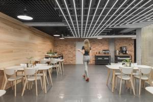 a woman walking through a restaurant with tables and chairs at Green Loft Gdynia in Gdynia
