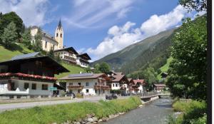 a town on a hill with a river and a church at Ferienwohnung Eichhorner in Außervillgraten
