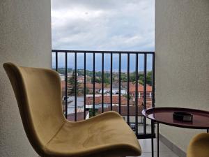 a chair and a table on a balcony with a view at Apartmani Optimist in Valjevo