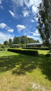 a large grass field with a building in the background at Carpinus I domek nad jeziorem in Łętowo