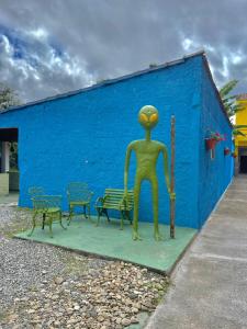 a statue of a person sitting on a bench next to a blue wall at Pousada ENCANTOS de PERUÍBE in Peruíbe