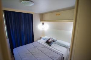 a small bedroom with a bed with a blue curtain at Belmonte Ranch in Belmonte Castello