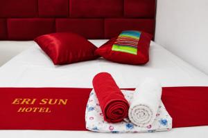 a bed with red and white towels and red pillows at Hotel Erisun in Vlorë