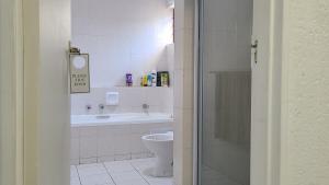 a white bathroom with a toilet and a sink at Light Hall in Johannesburg