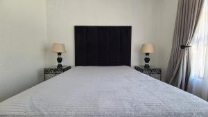 a bedroom with a large bed with two lamps at Light Hall in Johannesburg