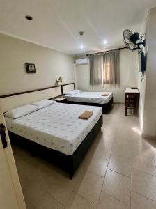 a bedroom with two beds and a table in it at Hotel Brasil Pindamonhangaba in Pindamonhangaba +23 photos