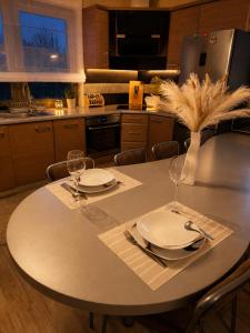 a kitchen with a table with two plates and wine glasses at Brzegowy Relaks in Mszana Dolna
