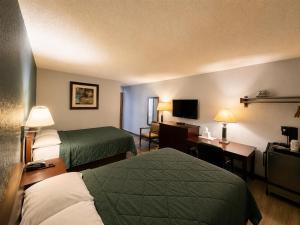 ein Hotelzimmer mit zwei Betten und einem Fernseher in der Unterkunft Corning Inn in Painted Post + 4 Fotos