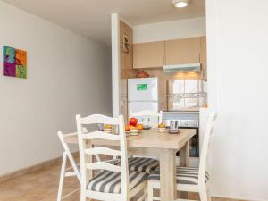 a kitchen with a wooden table and white chairs at Apartment Vermell-8 by Interhome in Platja d'Aro +16 photos