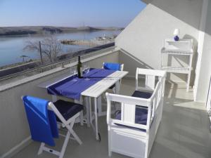 een tafel en stoelen op een balkon met uitzicht op het water bij Apartments Perla in Dinjiška