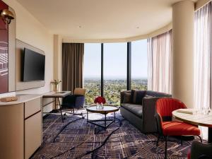 a living room with a couch and a tv at Mercure Melbourne Doncaster in Doncaster