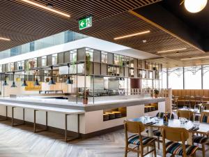 a restaurant with tables and chairs and a counter at Mercure Melbourne Doncaster in Doncaster