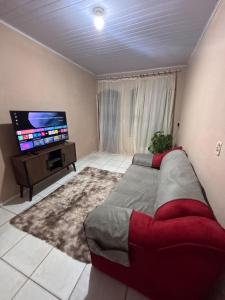 a living room with a bed and a flat screen tv at Refúgio da Sombra House in Rondonópolis