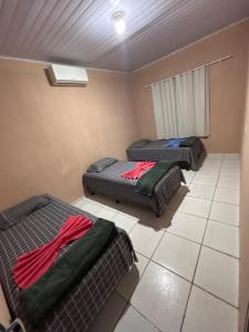 a room with two beds sitting on a tiled floor at Refúgio da Sombra House in Rondonópolis