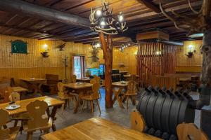 a restaurant with wooden tables and chairs and a chandelier at Koliba Hoděšovice in Býšť