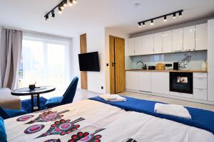 a bedroom with a large bed and a kitchen at Zygmuntówka - Apartamenty i Pokoje in Krościenko