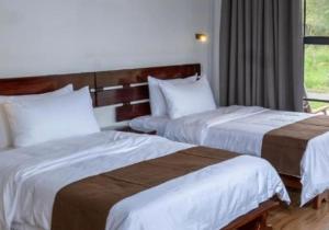 a hotel room with two beds and a window at Karatu Boutique Lodge in Karatu
