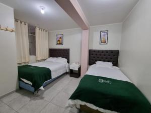 ein Schlafzimmer mit zwei Betten mit grüner Bettwäsche in der Unterkunft Hotel Patxy in Concepción