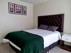 ein Schlafzimmer mit einem großen Bett und einer grünen Decke in der Unterkunft Hotel Patxy in Concepción