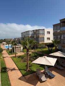 a patio with umbrellas and chairs in front of a building at Odyssée Atlantique Blue beach - Sidi Rahal - famille seulement in Sidi Rahal