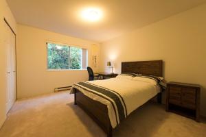 a bedroom with a bed and a desk and a window at Mountain and Ocean Views Art Deco House in West Vancouver