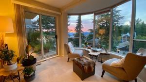 a living room with large windows and a table and chairs at Mountain and Ocean Views Art Deco House in West Vancouver