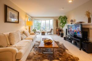 a living room with a couch and a tv at Mountain and Ocean Views Art Deco House in West Vancouver