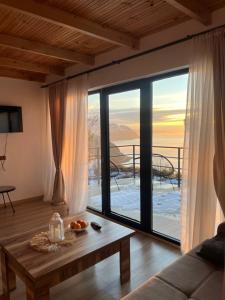 a living room with a table and a large window at Skidala Cottage in Batumi