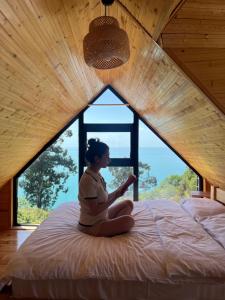 a woman sitting on a bed in front of a window at Skidala Cottage in Batumi +5 photos