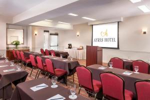 a conference room with tables and red chairs and a screen at Ayres Hotel Anaheim in Anaheim