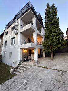 a white building with a tree in front of it at Layla's Home Free Parking in Sarajevo