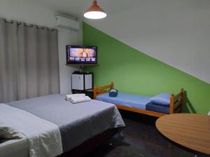 a room with two beds and a tv and a table at Pousada Flay 7 minutos do Aeroporto de Florianópolis in Florianópolis