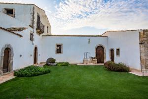 a large white house with a green yard at Casal Sikelio in Cassibile